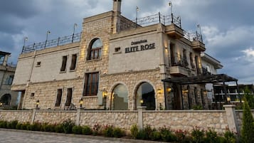 A stone building with the name 'Cappadocia ELITE ROSE' on the facade, featuring arched windows and a balcony.