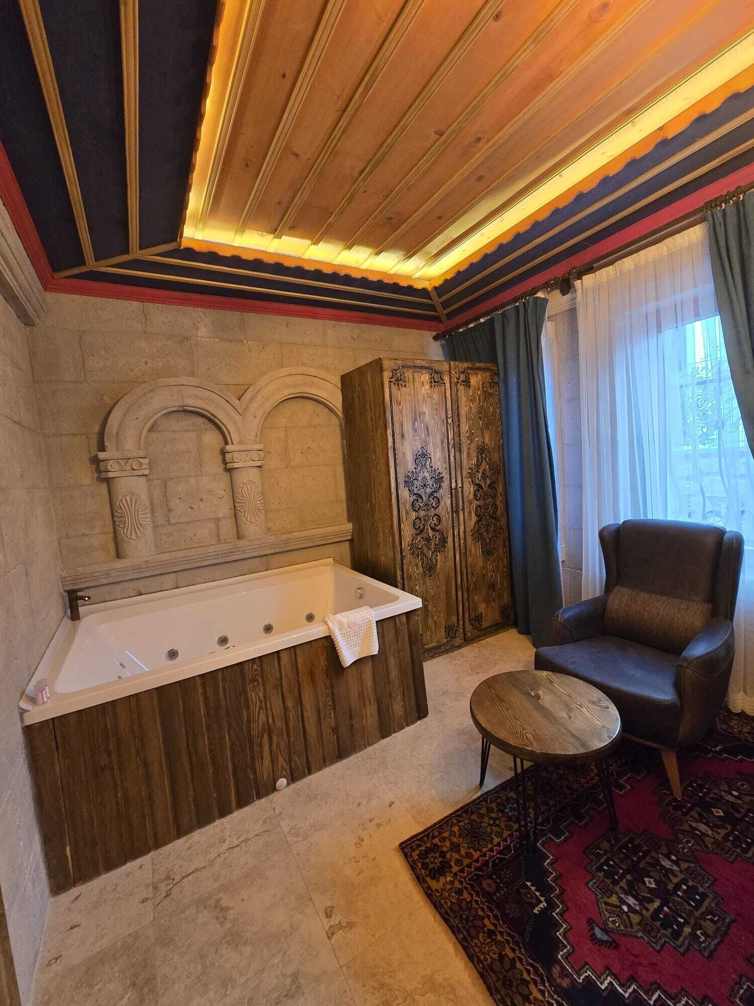 Un baño con una bañera independiente, una pared de piedra y un tocador de madera.