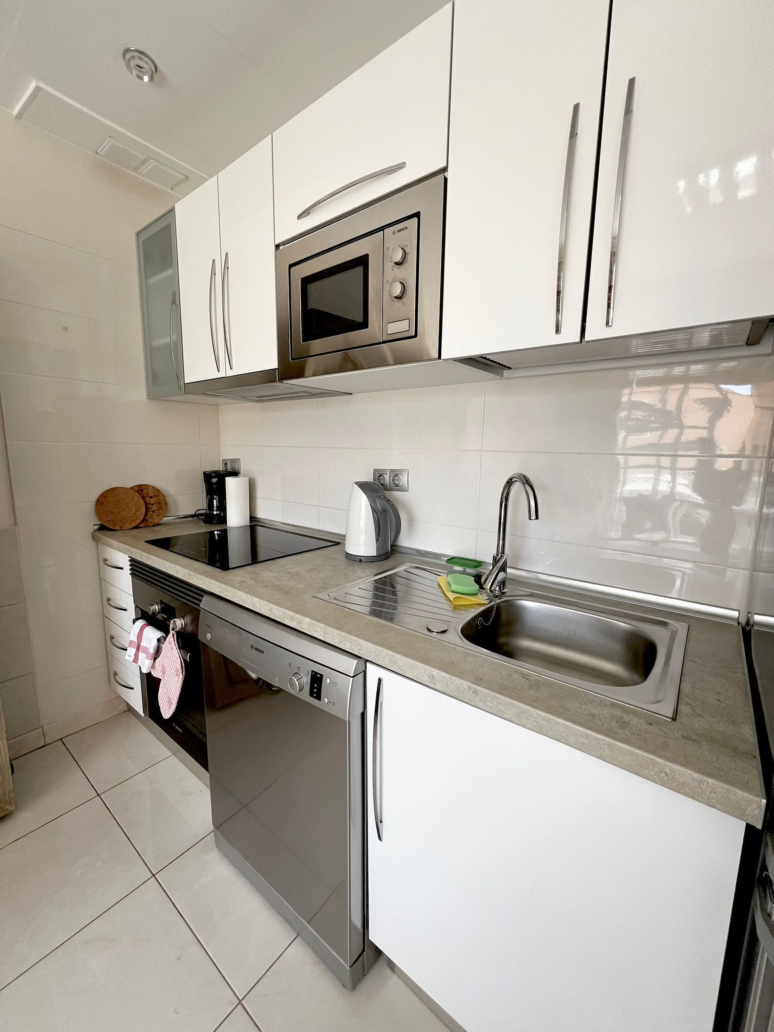 A modern kitchen with white cabinets, stainless steel appliances, and a dishwasher.