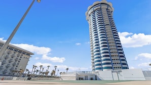 A tall, cylindrical hotel with multiple balconies, a flat roof, and a clear blue sky in the background. - Beautiful Oceanfront 2BDR/2BA @ Peck Plaza 5SE (Daytona Beach)