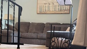 A staircase with wooden steps leading to a living area with a sofa and a lamp.