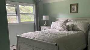 A bedroom with a bed, nightstand, lamp, and a framed picture on the wall.