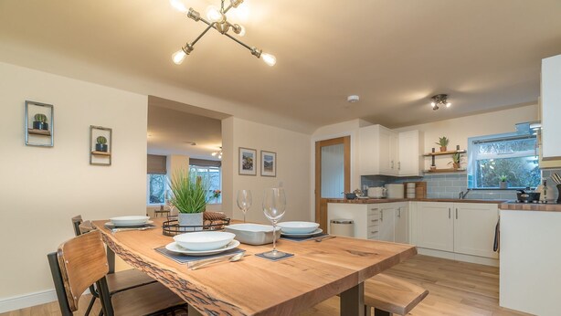 A modern kitchen with a wooden dining table, white cabinets, and a built-in oven.