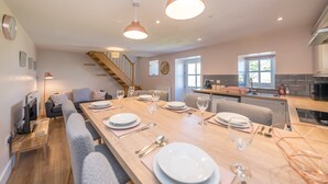 Una cocina moderna con una mesa de comedor de madera dispuesta para cuatro personas, equipada con platos, vasos y cubiertos.
