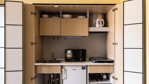 A compact kitchen with wooden cabinets, a built-in microwave, and a small refrigerator. - Gramsci 3 Studios by Wonderful Italy (Bologna)