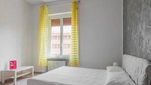 A bedroom with a bed, a bedside table, and a window with yellow curtains. - Gramsci 3 Studios by Wonderful Italy (Bologna)