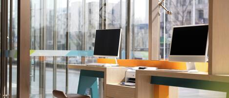 A modern office with two desktop computers, a printer, and a chair.
