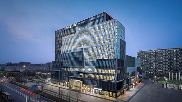 Un hôtel moderne doté d’une façade en verre, de plusieurs étages et d’une enseigne bien visible.