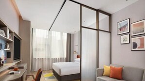 Une chambre d’hôtel moderne équipée d’un lit, d’un bureau, d’un canapé et d’un coin repas.