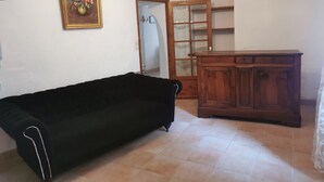 Une pièce avec un canapé noir, un meuble en bois et un tableau accroché au mur.