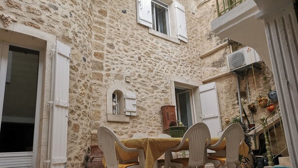 Un bâtiment en pierre doté d’une cour intérieure comprenant une table et des chaises, une fenêtre et une porte.