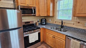 A modern kitchen with wooden cabinets, stainless steel appliances, and a granite countertop. - Cozy cabin in Brasher Falls, NY (Brasher Falls)