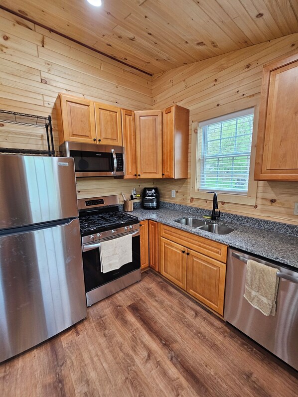 A modern kitchen with wooden cabinets, stainless steel appliances, and a granite countertop.