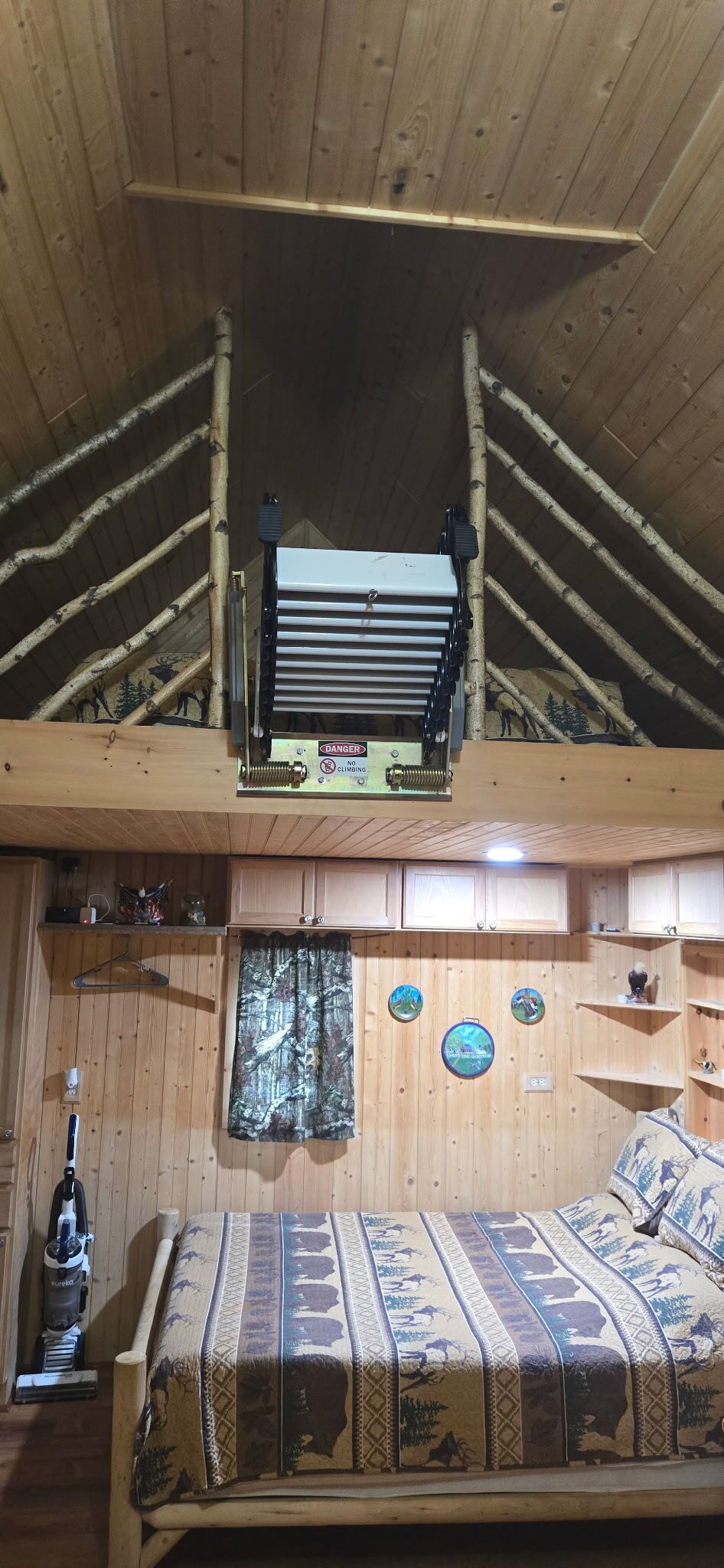 A room with a bunk bed, a ceiling fan, a vacuum cleaner, and a wall with three circular decorations.