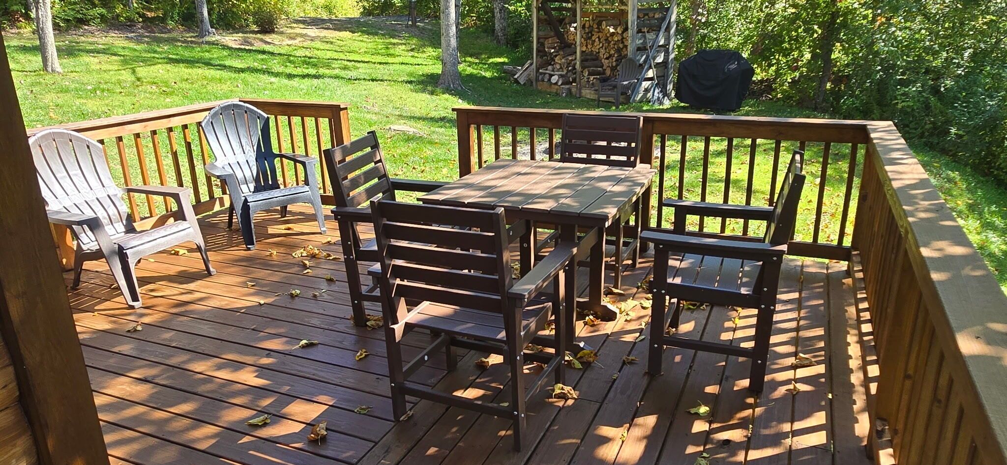 A wooden deck with a table and chairs, surrounded by a railing.