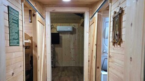 A wooden interior hallway with a ceiling fan, an air conditioning unit, and a kitchen area visible through an open door. - Cozy cabin in Brasher Falls, NY (Brasher Falls)