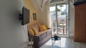 Una sala de estar con sofá, una mesa de centro, televisor y puerta corrediza de vidrio que da a un espacio exterior.