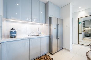 A modern kitchen with light blue cabinets, stainless steel appliances, and a marble countertop.
