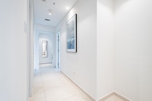 A modern, well-lit hallway with a framed artwork on the wall, leading to a room with a door at the end. - Waterfront 2BR Apartment in The Address Fujairah Residences Block C, Fujairah (Fujairah)