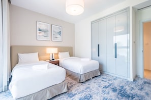 A hotel room with two beds, a nightstand with a lamp, a wardrobe, and two framed pictures on the wall. - Waterfront 2BR Apartment in The Address Fujairah Residences Block C, Fujairah (Fujairah)