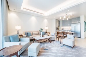 Una sala de estar moderna con sofá, reposapiés, mesa de centro y zona de comedor.