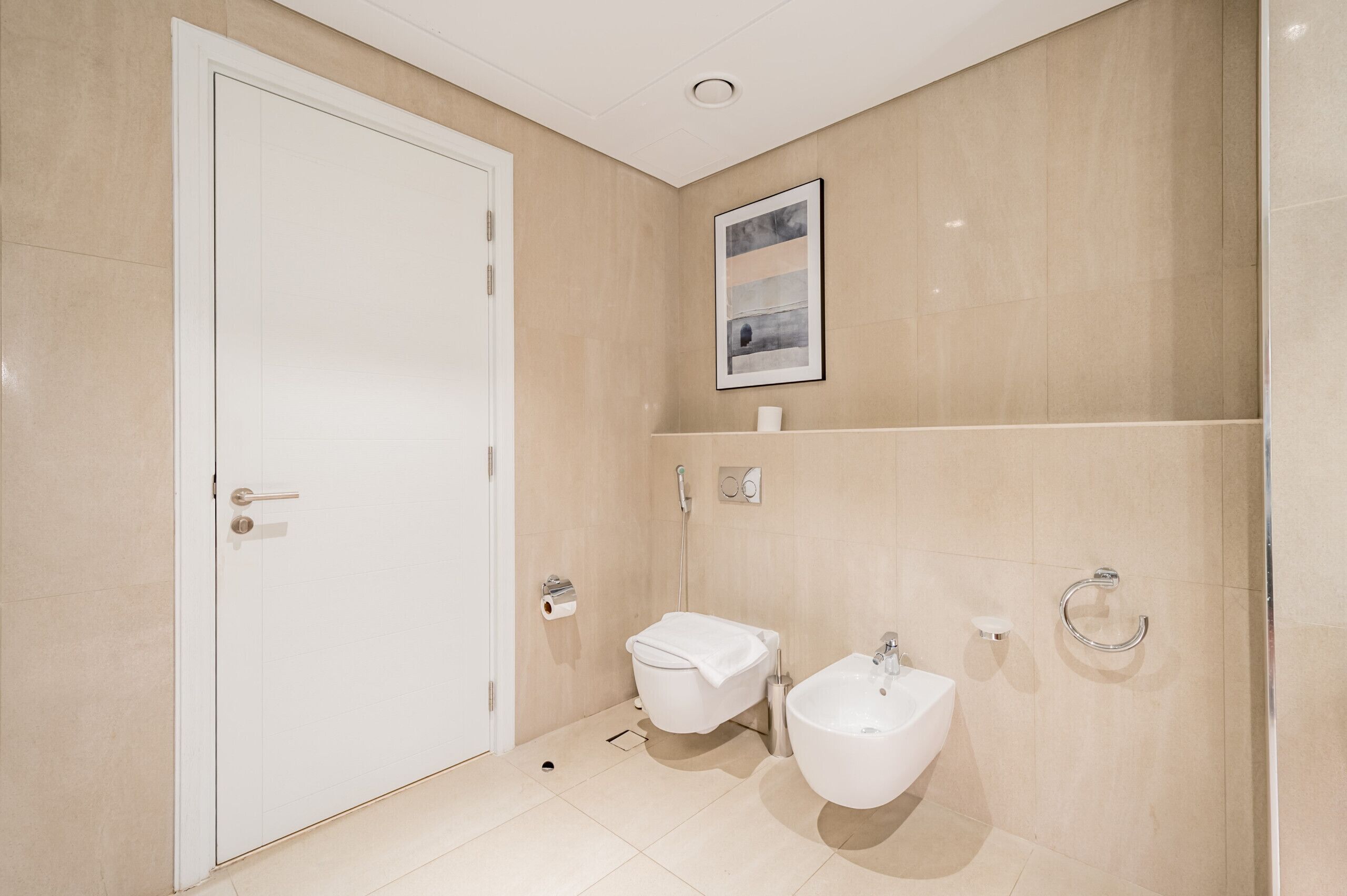 Un baño moderno con puerta blanca, inodoro, bidé y lavamanos.