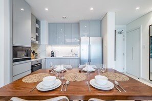 A modern kitchen with light blue cabinets, a built-in oven, and a refrigerator.