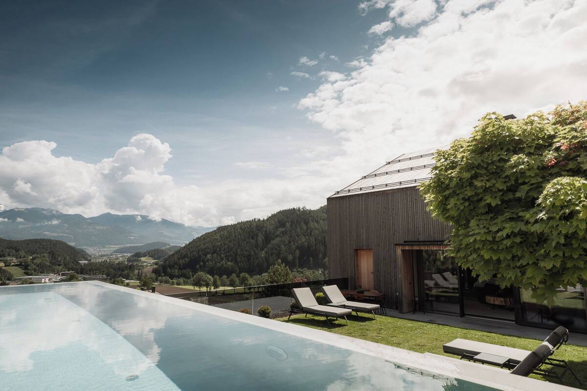 A modern pool area with lounge chairs and a view of mountains.
