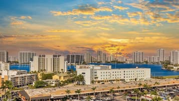 A cityscape with high-rise buildings, a marina, and a parking lot with palm trees.
