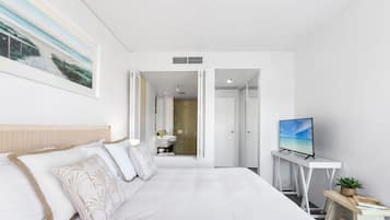 Habitación de hotel con una cama grande, un televisor, un escritorio pequeño y un baño visible a través de una puerta abierta.