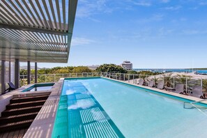 A rooftop infinity pool with a clear view of the ocean and buildings in the background. - Lux Waterfront - Prime Location Pool Gym Sauna (Cairns)