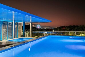 A modern outdoor pool area with a clear view of a Ferris wheel in the background. - Lux Waterfront - Prime Location Pool Gym Sauna (Cairns)