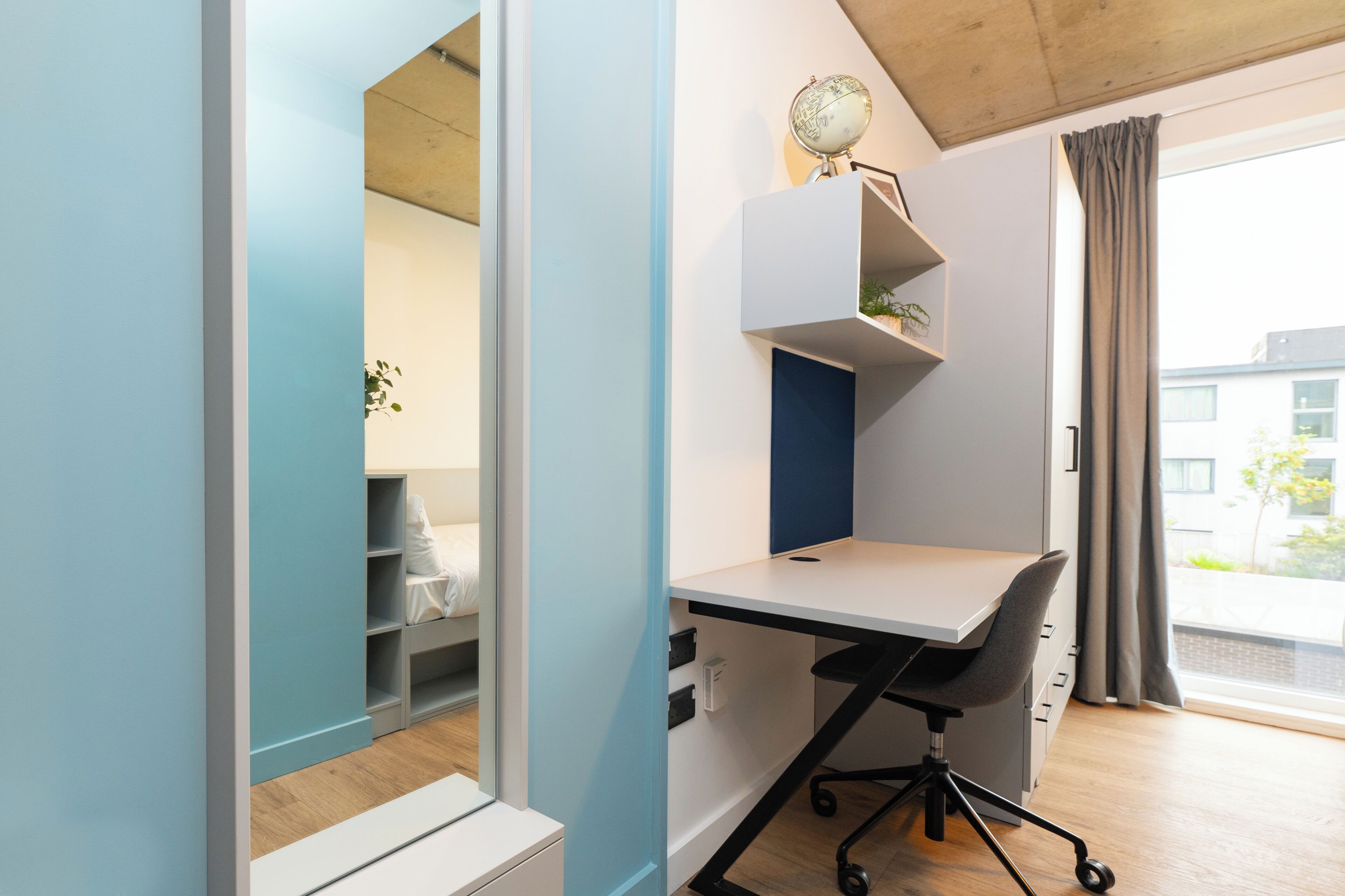 A modern room with a desk, chair, and a globe on the wall.
