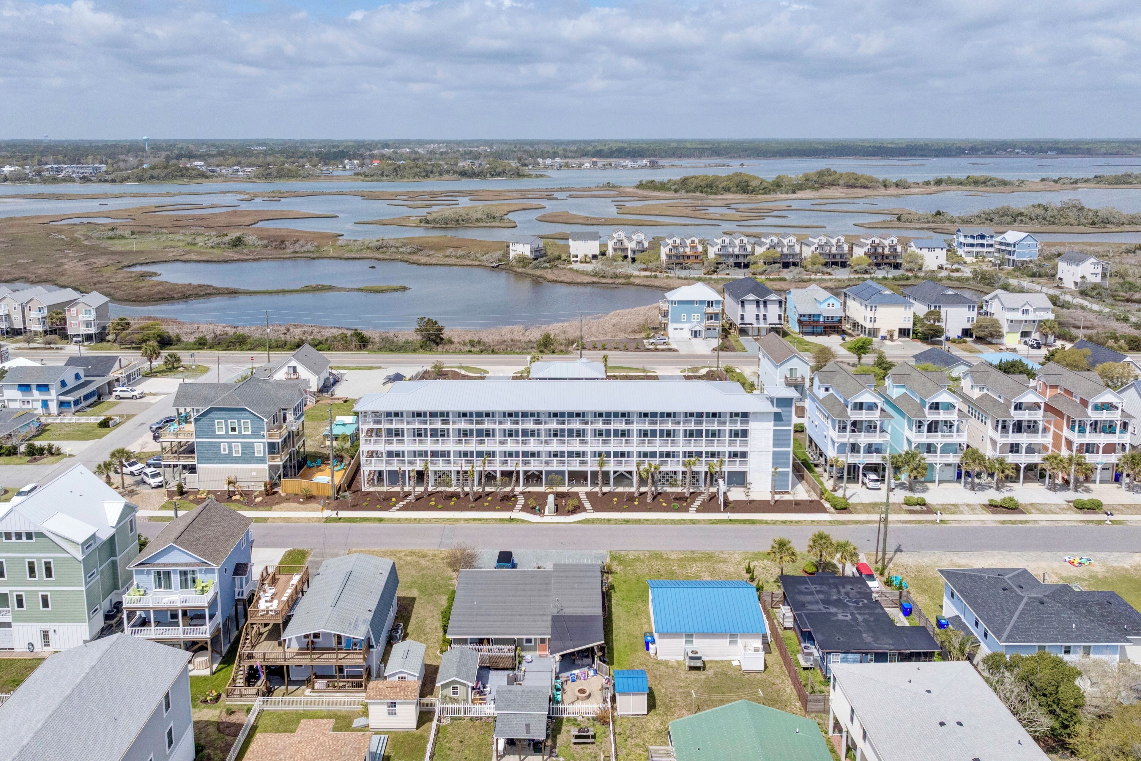 A residential area with houses and a large building, likely a hotel, with a view of a water body in the background.