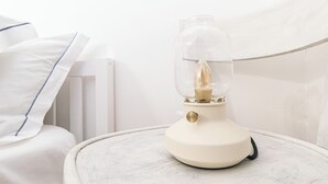 Ett nattduksbord med en lampa, en vit kudde och ett vitt element.