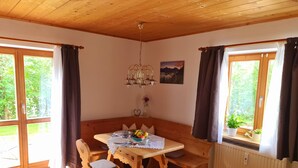 A wooden dining area with a table, chairs, and a bench. There is a radiator, a window with curtains, and a chandelier. - Ruhige Ferienwohnung in Bad Tölz (Bad Tölz)