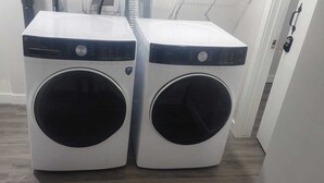 Two front-loading washing machines in a hallway. - A Cozy home away from home at South East Calgary (Calgary)