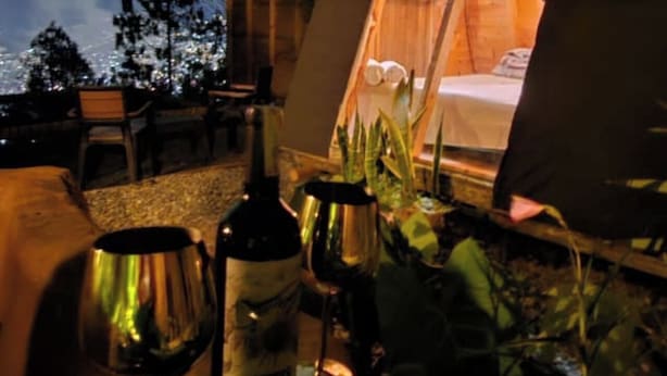 Zona d'estar a l'aire lliure acollidora amb una taula per a dos, una ampolla de vi i un got.