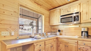 A wooden cabin kitchen with a microwave, coffee maker, and wooden cabinets. - Fox Creek Cottage located in Panguitch Lake (Panguitch Lake)