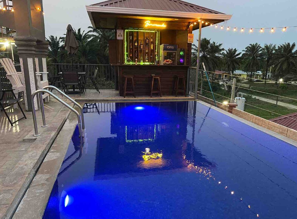 A pool area with a bar, lounge chairs, and a view of palm trees.