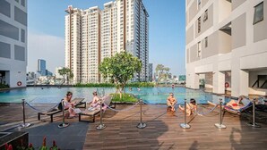 Un espace piscine aménagé sur le toit, avec des chaises longues et une vue sur les gratte-ciel.