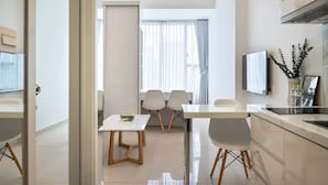 Une cuisine moderne avec un coin repas, un téléviseur fixé au mur et une vue sur l’extérieur par une fenêtre.