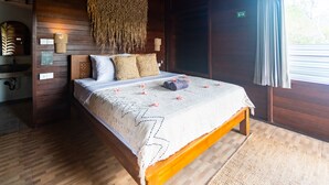 Une pièce en bois avec un lit, une lampe fixée au mur et une fenêtre avec des rideaux.