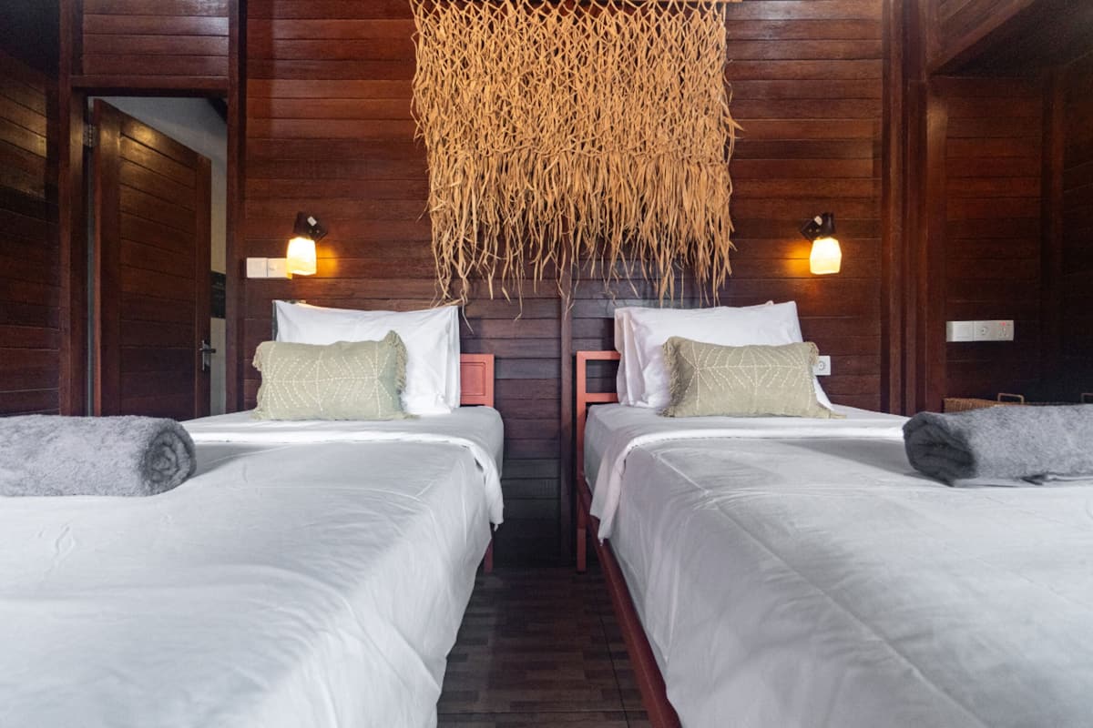 Habitación de hotel con dos camas, paredes de madera y un adorno colgante.