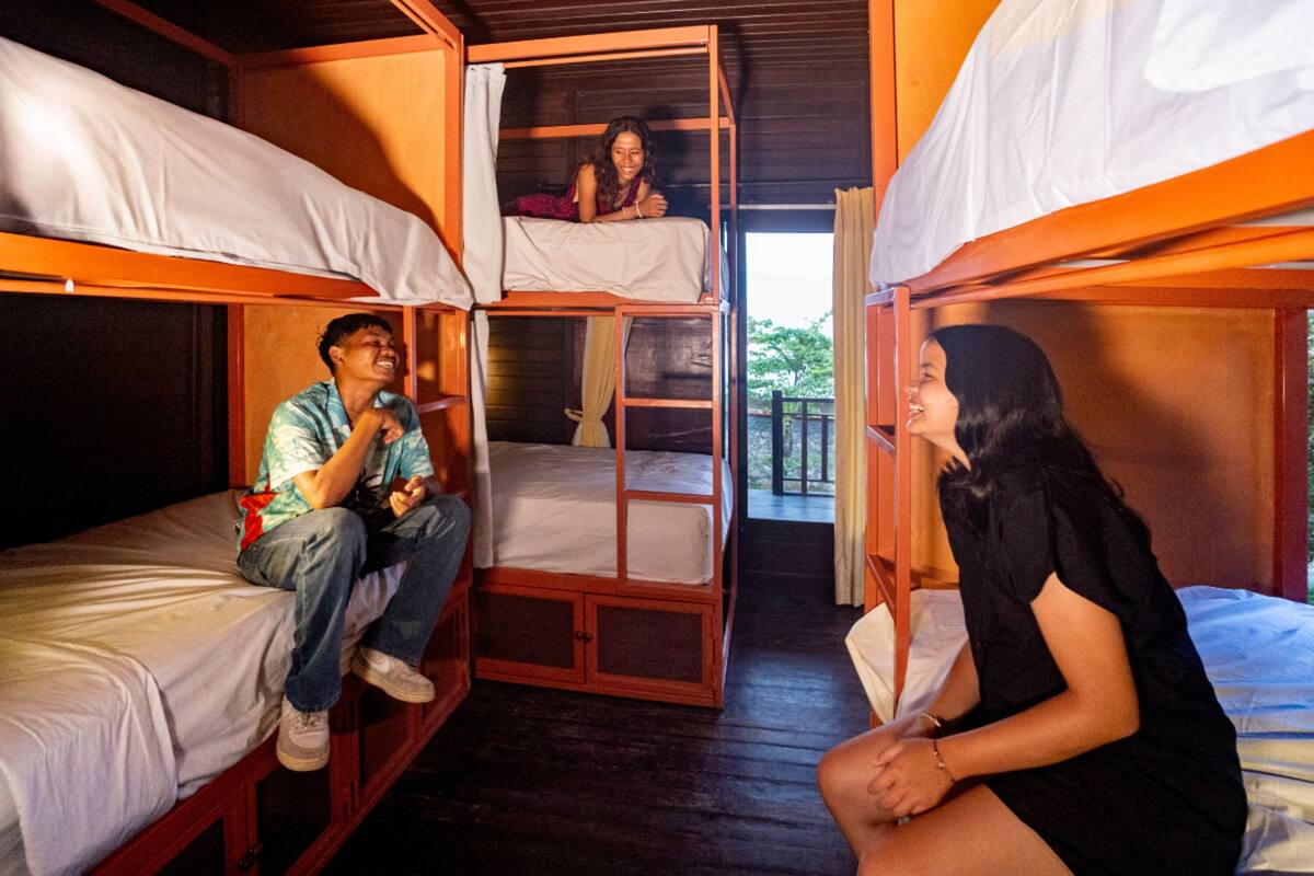 Habitación tipo dormitorio con literas, suelo de madera y balcón.
