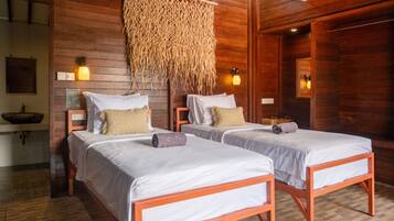 A room with two beds, wooden walls, a woven ceiling, and a small sink.