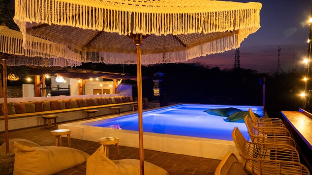 Un espace piscine comprenant un coin salon, une table et un parasol.
