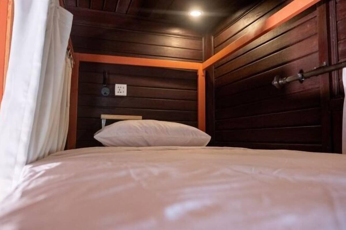 Una cama con cabecera, un enchufe y una puerta con pomo.