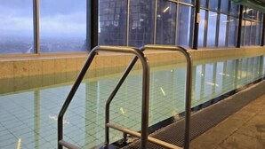Una piscina con barandales metálicos y amplias ventanas.