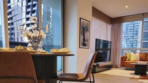 Una sala de estar moderna con comedor, que incluye una mesa redonda, dos sillas y un jarrón con flores.